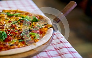 Italian fast food. Delicious  and appetizing hot pizza sliced and served on wooden platter with ingredients, close up view