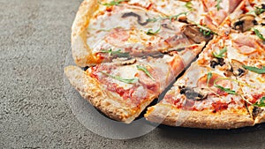 Italian fast food. Delicious hot pizza with ham and champignons sliced and served on brown concrete table, close up view. Menu