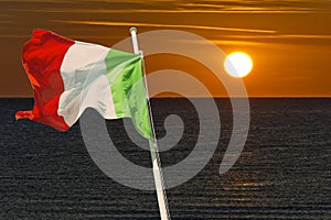 Italian flag wawing in the wind with sunrise as background