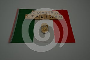 An Italian flag with written,  compra italiano which in English means, buy Italian and with some coins photo