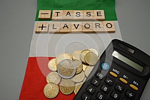 An Italian flag with written meno tasse piu lavoro,which in English means less tax plus work with coins and calculator photo