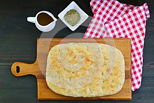Italian Focaccia Bread with Dried Herbs on the Breadboard