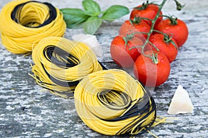 Italian food background with tomatoes, basil, spaghetti, parmesan, olive oil. Ingredients on old wooden table.