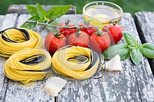 Italian food background with tomatoes, basil, spaghetti, parmesan, olive oil. Ingredients on old wooden table.