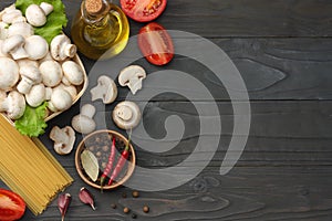 Italian food background, with tomatoes, parsley, spaghetti, mushrooms, oil, lemon, peppercorns on dark wooden table. Top view
