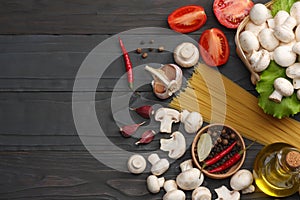 Italian food background, with tomatoes, parsley, spaghetti, mushrooms, oil, lemon, peppercorns on dark wooden table. Top view