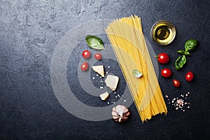 Italian food background with uncooked spaghetti, tomato, basil leaves, cheese, garlic and olive oil for cooking pasta
