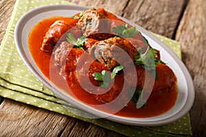 Italian food: beef steak stuffed with parsley and parmesan cheese in tomato sauce close-up on a plate. horizontal