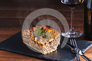 Italian food fresh hot steaming lasagna pasta served on wooden table and slate plate