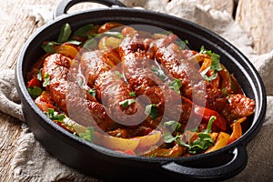 Italian food grilled sausage with grilled peppers, onions, herbs and tomatoes closeup in a frying pan. horizontal