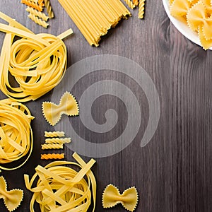 Italian food ingredients frame with various pasta, vegetables, mushrooms, olives. Flat lay on dark wooden background