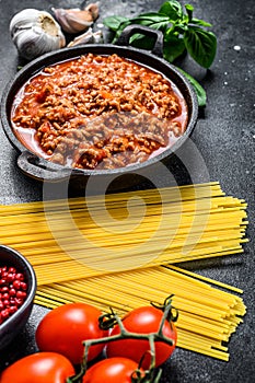 Italian food ingredients for Spaghetti Bolognese. Raw pasta, Basil, ground beef, tomatoes. Black background. Top view