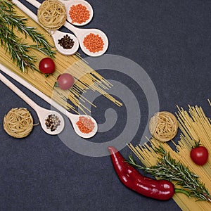 Italian food ingredients.Still life of cooking pasta on a black background top view. Wooden spoons with spices. Frame of products