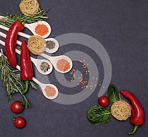 Italian food ingredients.Still life of cooking pasta on a black background top view. Wooden spoons with spices. Frame of products