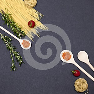 Italian food ingredients.Still life of cooking pasta on a black background top view. Wooden spoons with spices. Frame of products