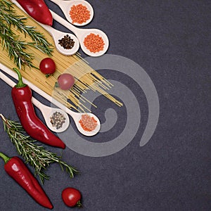 Italian food ingredients.Still life of cooking pasta on a black background top view. Wooden spoons with spices. Frame of products