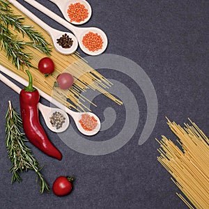 Italian food ingredients.Still life of cooking pasta on a black background top view. Wooden spoons with spices. Frame of products