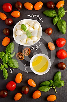 Italian food ingredients â€“ mozzarella, tomatoes, basil and olive oil on black background