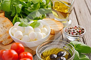 Italian food ingredients â€“ mozzarella, tomatoes, basil and olive oil on rustic wooden background