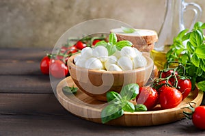 Italian food ingredients â€“ mozzarella, tomatoes, basil and olive oil on rustic wooden table.