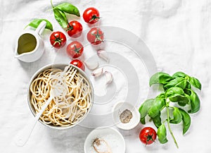 Italian food pasta background with copy space on white background, top view. Basil, whole grain spaghetti, cherry tomatoes, olive