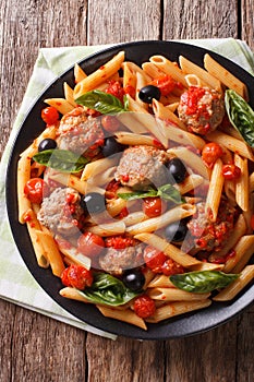 Italian Food: Pasta with meatballs, olives and tomato sauce closeup. Vertical top view