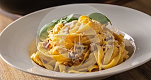 Italian food pasta tagliatelle carbonara with pancetta parmesan egg yolk and basil leaves