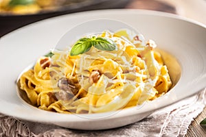 Italian food pasta tagliatelle carbonara with pancetta parmesan egg yolk and basil leaves