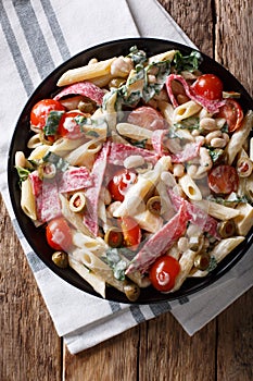 Italian food: penne pasta with salami, cheese, and vegetables cl