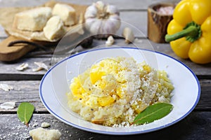 Italian food. Plate of yellow bell pepper risotto and grated parmesan cheese