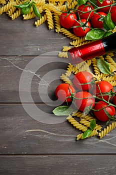 Italian food - raw fusilli, tomato, basil and wine on the wooden table