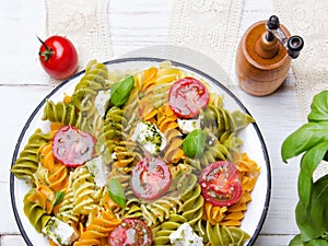 Italian food - Salad with colorful pasta, cherry tomatoes, feta cheese and fresh basil