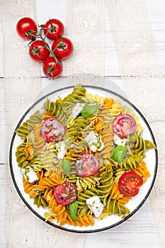 Italian food - Salad with colorful pasta, cherry tomatoes, feta cheese and fresh basil