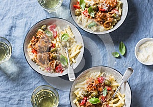 Italian food table. Pasta with slow cooker chicken with olives and sweet peppers, white wine. On a blue background