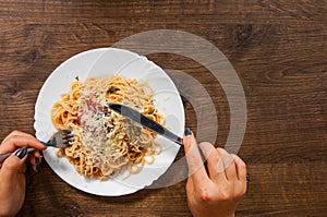 Italian food. woman hand holding fork with spaghetti bolognese in white plate on wooden table. with copy space