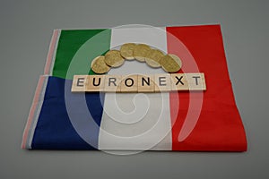 An Italian and a French flag with euro coins,with written,Euronext, which would be the name of the agreement ,Italy and France photo