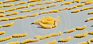 Italian fusilli, rotini or scroodle macaroni pasta food background texture. Close up, pasta spirals on gray background