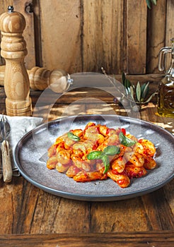 Italian Gnocchi with tomato sauce and basil on wooden background