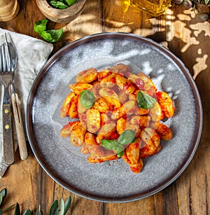 Italian Gnocchi with tomato sauce and basil on wooden background