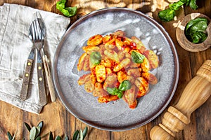 Italian Gnocchi with tomato sauce and basil on wooden background