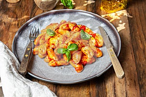 Italian Gnocchi with tomato sauce and basil on wooden background