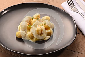 Italian gnocchi with white sauce on black plate