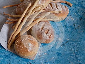 Italian gressini bread sticks and bread. Delicious aromatic pastries on a blue textured background.