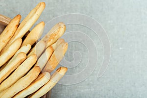 Italian grissini dry breadsticks in wooden bowl on blue-grey colored tablecloth blurred