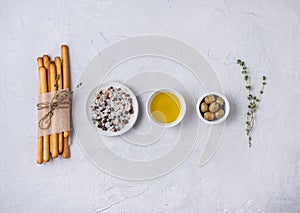 Italian grissini stick bread with salt, olive oli and thyne on white beton table