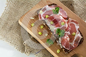 Italian ham coppa or capicola on dark bread on a wooden cutting