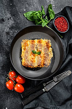 Italian homemade pasta cannelloni with beef and tomato sauce. Black background. top view