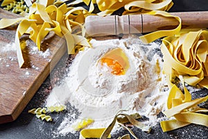 Italian homemade pasta with wheat flour and egg on black background