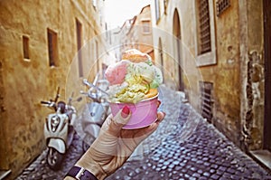 Italian ice - cream cone held in hand on the background of on vintage street atmosphere