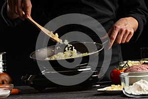 Italian lasagna, cooking process. Chef fries onions in a pan, freezes in motion, against the background of ingredients. Home